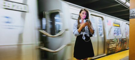 Portrait of young woman in casual clothes, employee at underground train station looks at camera and...