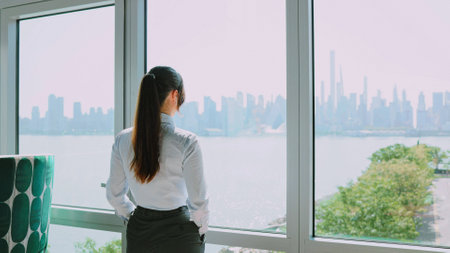 Portrait of cute cheerful professional Caucasian businesswoman in classy suit looking at window in...