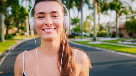 Portrait of fit girl preparing for running in workout clothes looking at camera smiling. Beautiful...