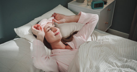 Waist up portrait view of the pleasant woman started her morning at the bed. Woman wearing pajama...