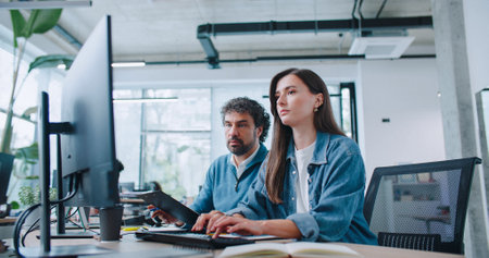 Handsome Caucasian leader checking completed working task on computer. Young girl presenting her...
