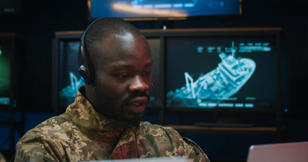 Close up of African American young man in headset sitting at laptop computer and talking via...