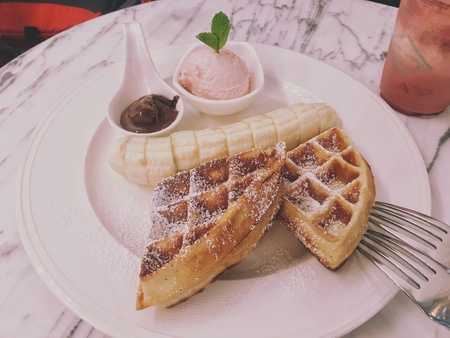 Sweet dish for afternoon break, hot waffles, banana, strawberry cream and hot chocolate on the white dish.の素材