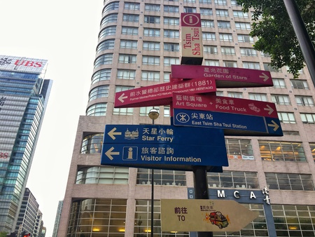 Hong kong, China - 22 June, 2018: The group of sign label guide the way for tourist with the city building background at Tsim sha Tsui, Hong kong, China.の素材