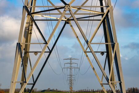 Hydroelectric towers in agricultural field against blue sky with white clouds