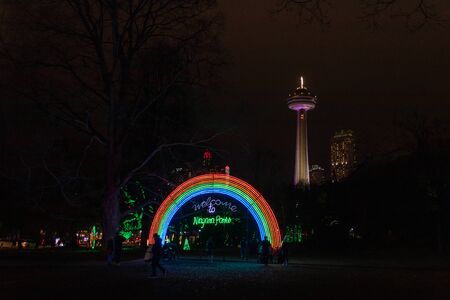 Niagara Falls, Ontario, Canada, December 27, 2019: Illuminated Parks Ontario Rainbow and Skylon Tower at night during Winter Festival of Lightsの写真素材