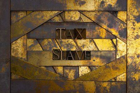 Photo of real authentic typeset letters forming Tax Slave text on vintage textured grunge copper and...