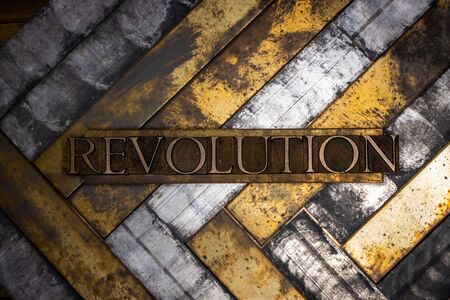 Photo of real authentic typeset letters forming Revolution text on vintage textured grunge copper and black backgroundの写真素材