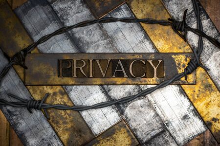 Photo of real authentic typeset letters forming Privacy text with barb wire on vintage textured grunge silver and gold backgroundの写真素材