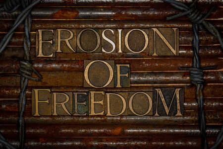 Photo of real authentic typeset letters forming Erosion of Freedom text on vintage textured rusty...