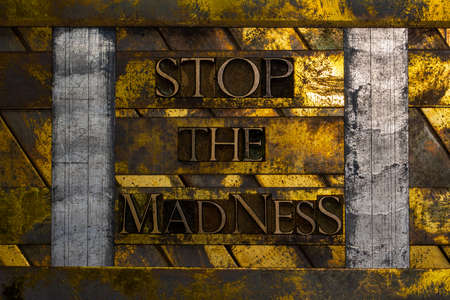 Stop The Madness text formed with real authentic typeset letters on vintage textured silver grunge copper and gold backgroundの写真素材
