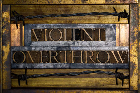 Photo of real authentic typeset letters forming Violent Overthrow text on vintage textured grunge copper and gold backgroundの写真素材