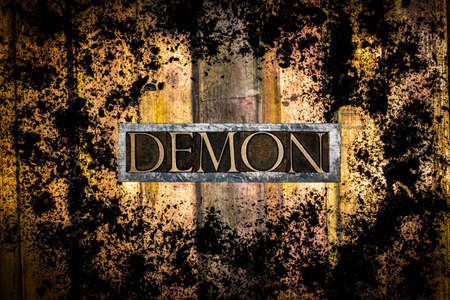 Demon text message on textured and ground charcoal covered grunge bronze background
