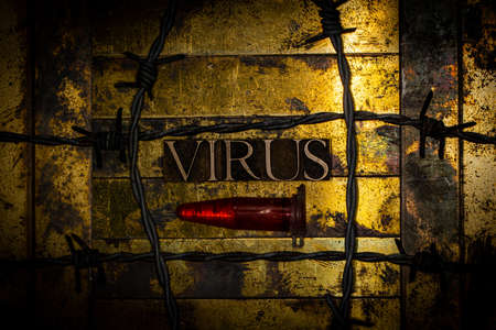 Virus text message next to laboratory vial filled with red fluid surrounded by barbed wire on textured grunge copper and vintage gold backgroundの写真素材