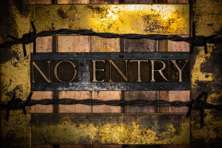 No Entry text message on vintage textured grunge copper and gold background lined with barbed wireの写真素材