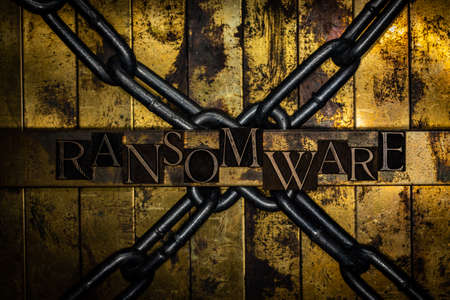 Ransomware text with steel chains on vintage textured silver grunge copper and gold background