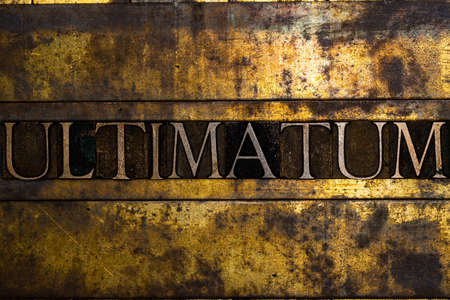 Ultimatum text message on textured grunge copper and vintage gold backgroundの写真素材