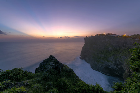 Pura Luhur Uluwatu Temple, Bali on cliffs above blue tropical sea at sunsetの写真素材