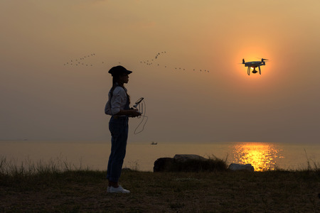 drone flying practice by girl on beach at sunset silhouetteの写真素材