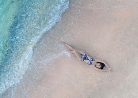 Woman enjoy on the beach at rim of sea edge in aerial viewの写真素材