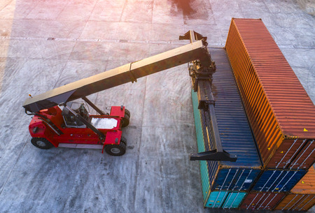 container stacker forklift working on lifting unit of container in yard in aerial view