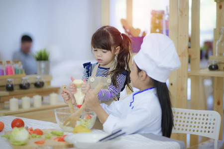 kids enjoy practice making salad together in the kitchenの写真素材
