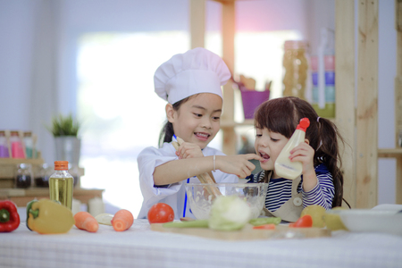 kids enjoy practice making salad together in the kitchenの写真素材