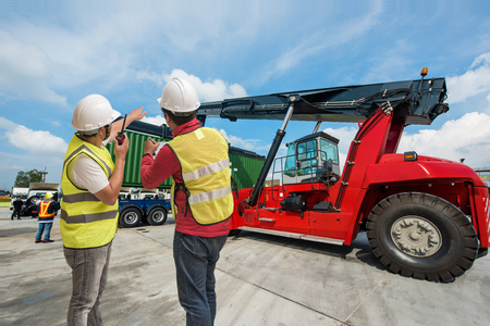 forklift lifting on the container to the trailer in yard, under foreman control in charge