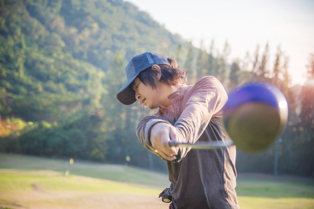 man golf player at downswing after hit golf ball away from tee off to the fairwayの写真素材