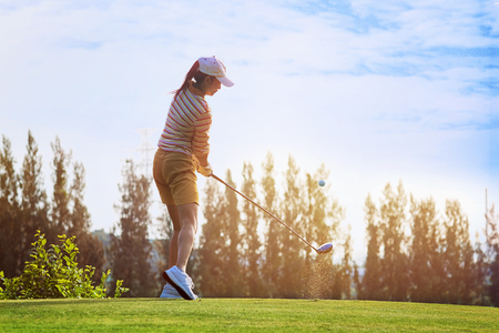 Fluffing of golf ball and tee flying away from the teeing ground impact by the woman golfer player after swing plane of proper stance addressing the ballの写真素材