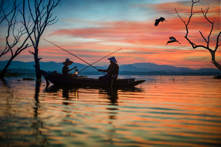 silouette local village fishering man and son holding fishing hook for fishing together in the lake at early sunrise in back groundの写真素材