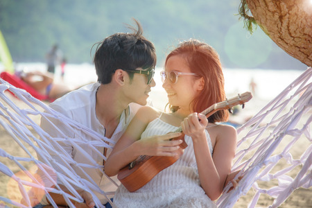 couple lover in romantic honeymoon sitting on swing hammock at the sea beach, anniversary and valentine occasionの写真素材