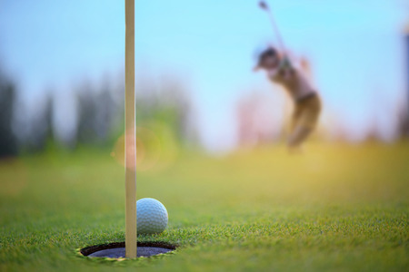golf ball atmost on the edge of the hole on the green by golf player hit the ball from apron green to the holeの写真素材