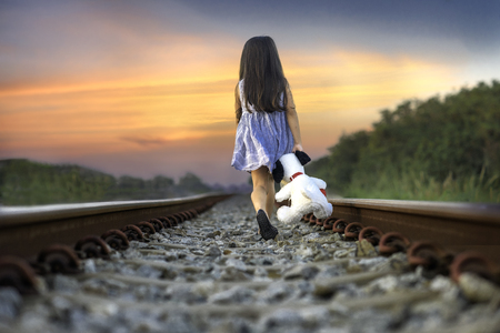 a little girl run away home on the railway, walking lonely ahead without destinationの写真素材