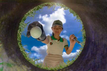 View from bottom of the golf hole, Golf ball in hand of woman player takes out from the hole after completed putting winner in shotの写真素材