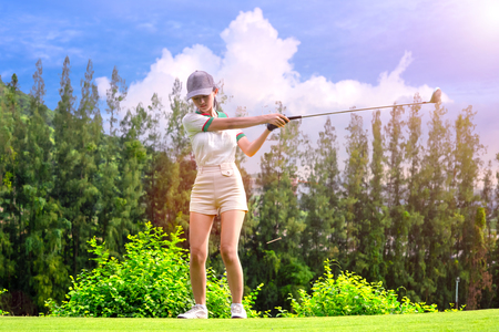 Young woman golfer just hit golf ball by wood driver from T-off away to the fairway destination winnerの写真素材