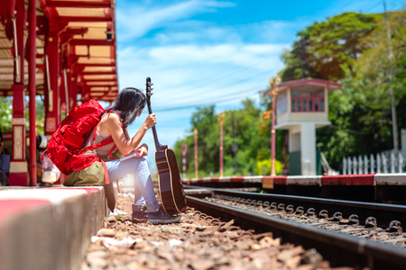 tourist woman sitting on the railway station looking for the incoming train, find destination for tourist traveling in holiday vacationの写真素材