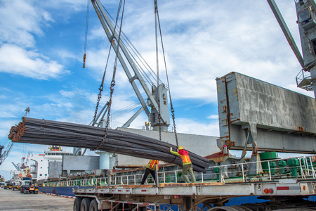 bundle of steel rod being loading discharging in port terminal, handle by gang of stevedore labor , shipment cargo in transition from land and sea transport servicesのeditorial素材