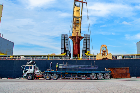 bundle of steel slab sheet being loading discharging in port terminal, handle by gang of stevedore...