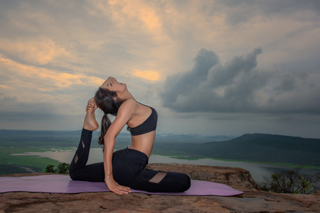woman practice yoga training on the top peak of mountain, river and lake in background