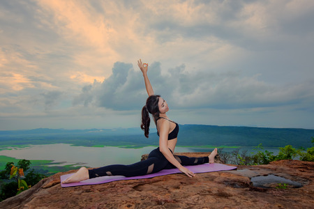 woman practice yoga training on the top peak of mountain, river and lake in backgroundの写真素材