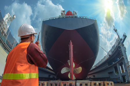 supervisor, foreman, inspector, surveyor takes final inspection of the cleaning, repairing, recondition of over hull of the commercial ship in dry dock yard, ready to delivery the ship to the seaの写真素材