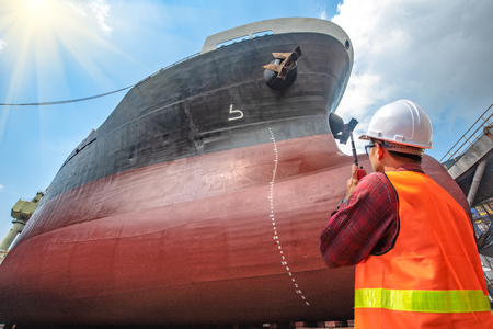 supervisor, foreman, inspector, surveyor takes final inspection of the cleaning, repairing, recondition of over hull of the commercial ship in dry dock yard, ready to delivery the ship to the seaの写真素材