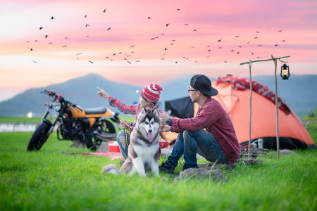 couple lover motorbike in moment sweet at countryside with campfire in meadow of lake sideの写真素材