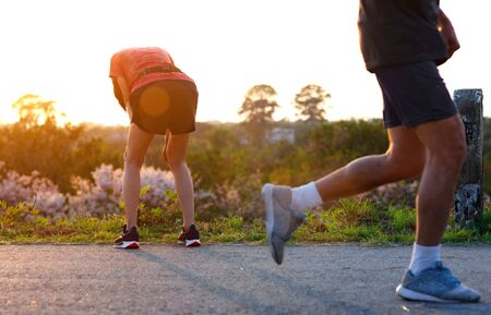 woman tired on running jogging exercise by hand resting on the knees, workout running of woman unfit and tired oftenの写真素材