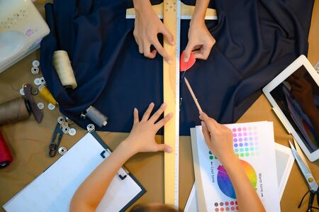 top view hands of a fashion designer at work with cloth fabric. Professional tailor measuring...