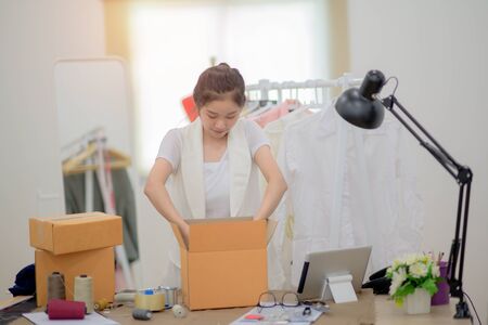 woman working alone in packing goods into boxes containers, ready to delivery to customer under rush at order and services, in time delivery by courier servingの写真素材