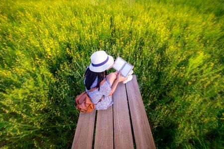 woman girl enjoy reading book in middle of wildflowers fieldの写真素材