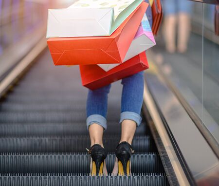 shopping bags in hand of happy woman enjoy walks upon escalator in shopping mall center, buying and shopping consumerism with many bags holding are in handsの写真素材