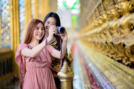 young tourist women enjoy taking picture of the palace temple in Bangkok of Thailand, Emerald Buddha Temple, Wat Phra Kaew, Bangkok Royal Palace popular tourist placeの写真素材